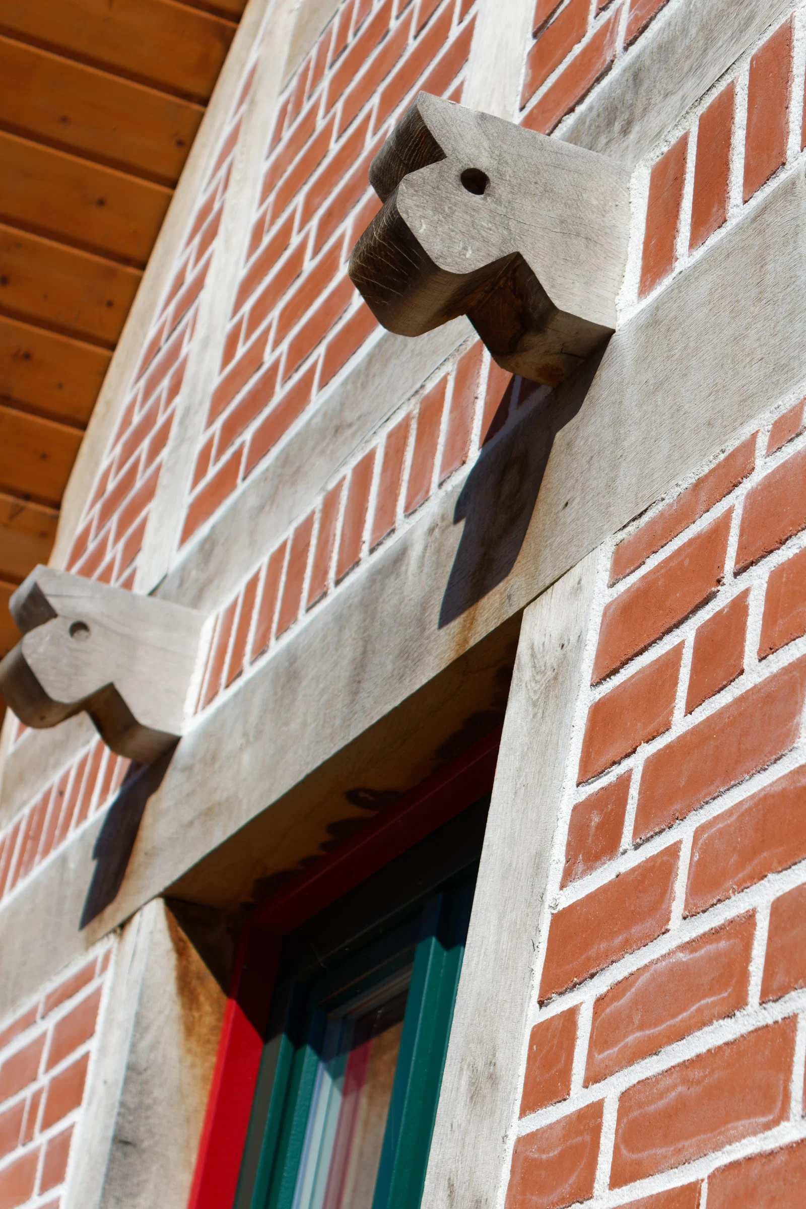 Detail der Backsteinfassade mit hellem Holz und grünem Fensterrahmen